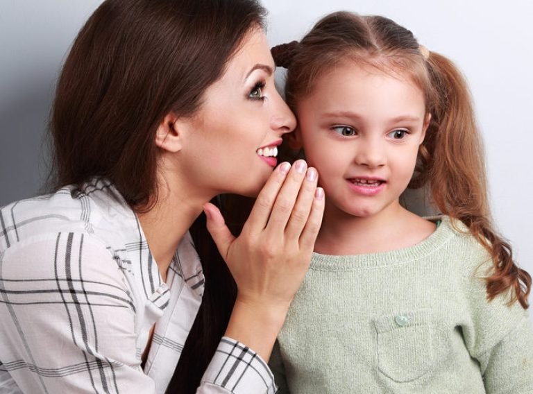 Woman Whispering To Young Girl