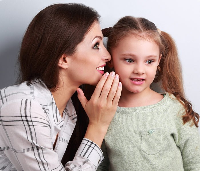 Woman Whispering To Young Girl